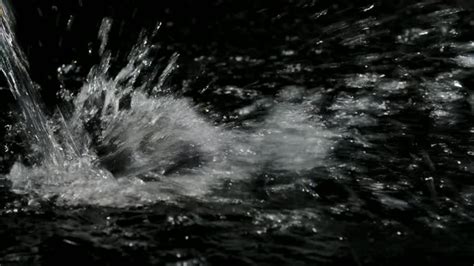 vibrant water falling  splashing  dark surface  slow motion