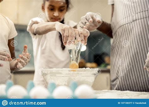 cute dark haired daughter beating egg cooking with father