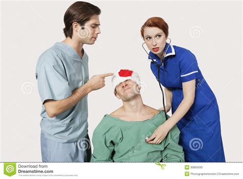 Male Doctor With Female Nurse Examining An Injured Patient