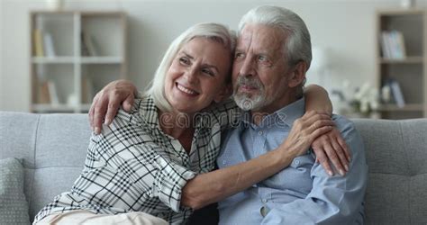 Elderly Loving Couple Hugging Seated On Sofa At Home Stock Video