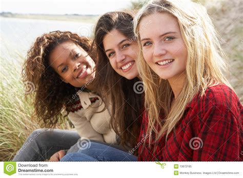 three teenage girls sitting in sand dunes together royalty