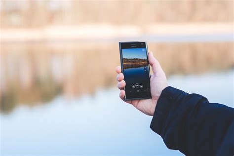 man taking photo of a lake with mobile phone · free stock