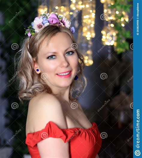 beautiful blonde model in red dress posing at christmas tree stock