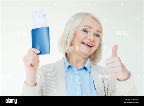 portrait of smiling senior woman showing passports with tickets and