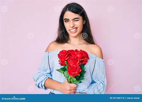 Brunette Teenager Girl Holding Flowers Winking Looking At The Camera