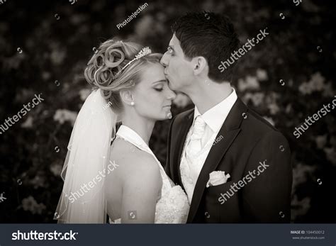 Groom Is Kissing His Bride Very Tender On Forehead Black