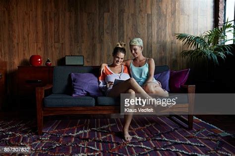 Lesbian Couple Sitting Together In Couch And Looking At Digital Tablet