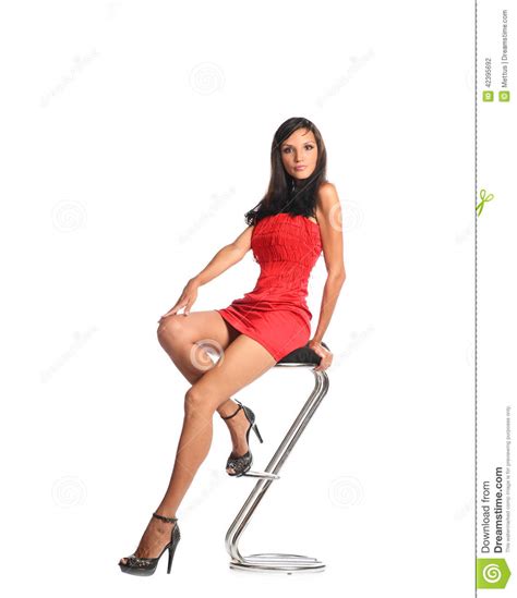 confident woman sitting on stool and looking at camera