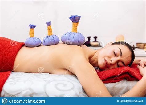 pleasant dark haired woman with flawless skin resting on massage bed