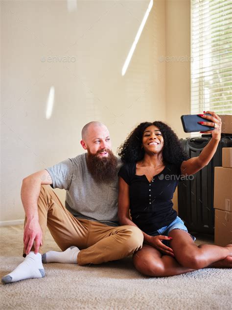 Interracial Couple Taking Selfie Together While Moving Into New Home