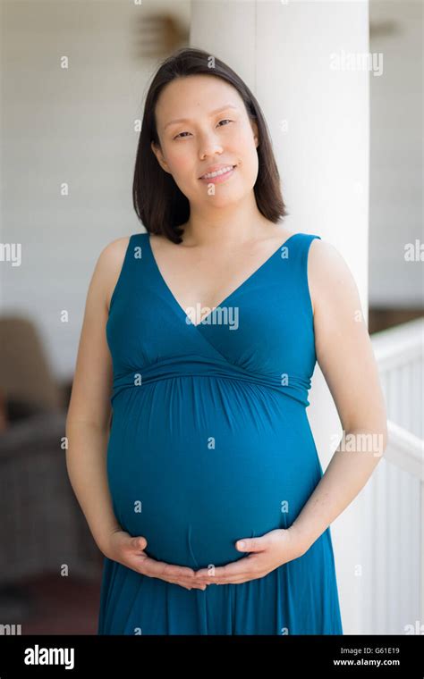 Portrait Of Happy Young Pregnant Chinese Woman On The Front Porch Stock