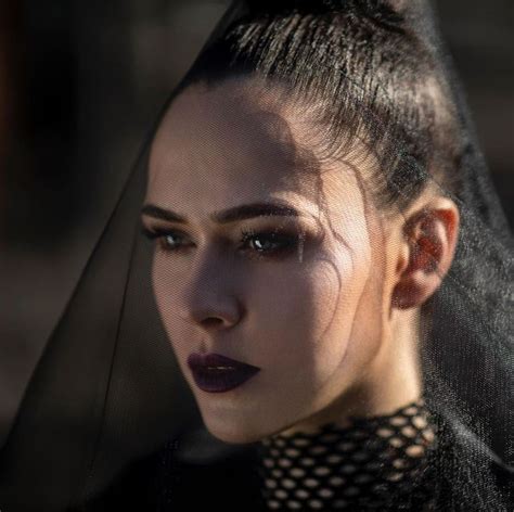 A Woman With Dark Makeup And Veil On Her Head