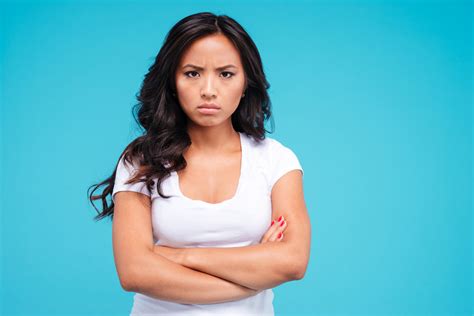 angry pretty asian woman standing with arms crossed isolated on the