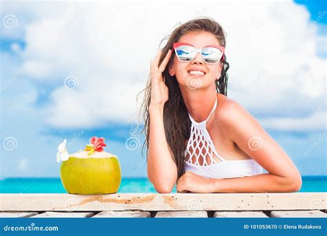 woman in bikini and sunglasses with fresh coconut cocktail relaxing on