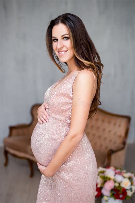 portrait of beautiful pregnant woman posing in evening dress stock