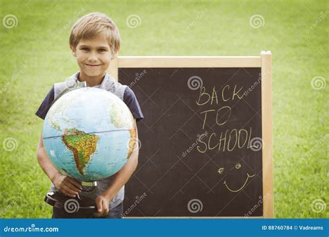 schooljongen met een bol tegen het bord onderwijs terug naar schoolconcept stock foto image