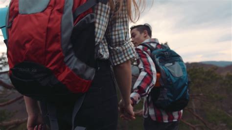 Back View Of A Blonde Charming Girl With A Backpack Holding Hand Of Her