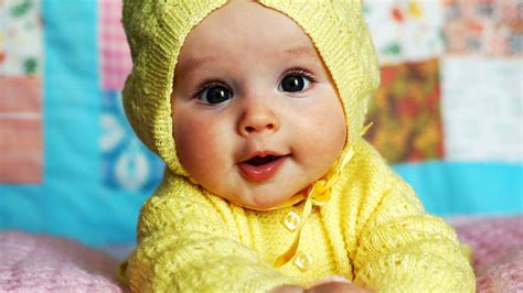 cute baby  wearing yellow knitted wool dress lying   bed