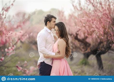 Romantic Bridegroom Kissing Bride On Forehead While Standing Against