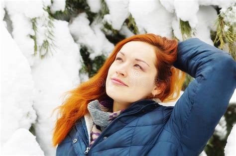 happy beautiful redhead girl has a rest in snowy pine forest stock