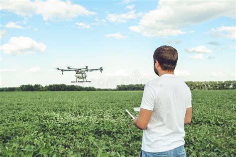 young man operating  flying drone octocopter   green field stock image image