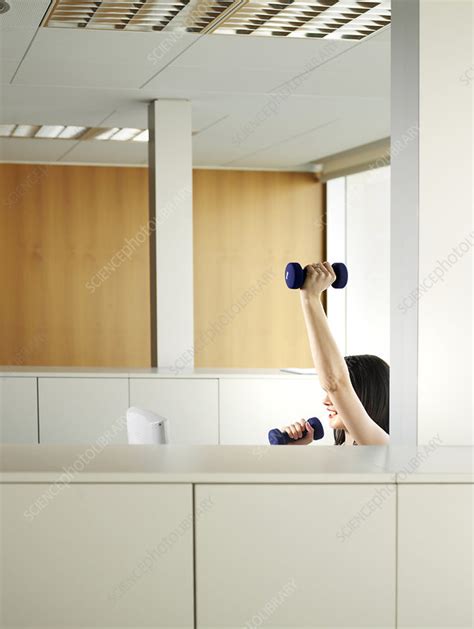 woman sitting in office lifting weights stock image