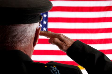 Senior Veteran Man In Military Uniform Saluting American Flag Stock