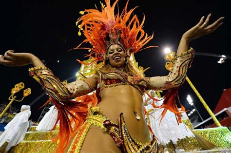 A Woman Dressed In An Orange And Gold Costume With Feathers On Her Head