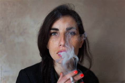 Attractive Woman Blowing Cigarette Smoke Del Colaborador De Stocksy