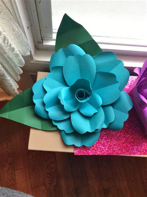 paper flower sitting  top   cardboard box    purple gift bag