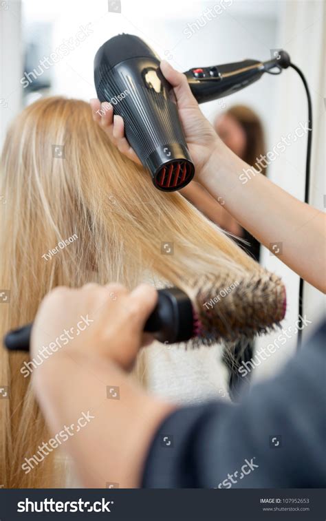 Close Up Of Hairdressers Hands Drying Long Blond Hair With Blow Dryer