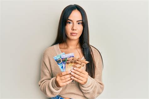 young beautiful hispanic girl holding canadian dollars relaxed