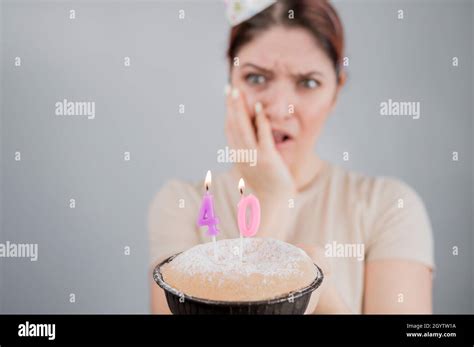 unhappy woman holding a cake with candles for her 40th birthday the
