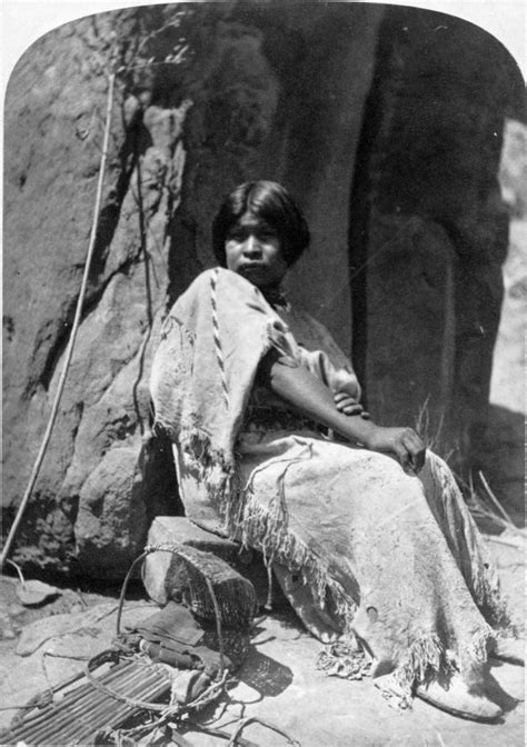 A Native American Paiute Woman Is Seated On A Rock Next