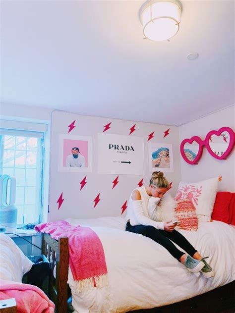 A Woman Sitting On Top Of A Bed In A Room With Pink And White Walls