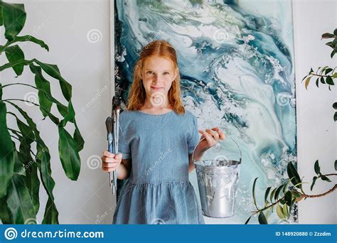 portrait of shy teenage redhead girl with bunch of brushes