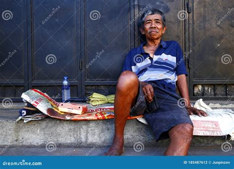A Mature Filipino Man Rests On A Sidewalk And Poses For The Camera
