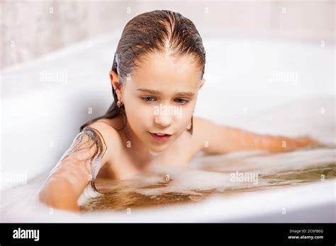 little cute caucasian girl bathes in a bathtub with foam and has fun