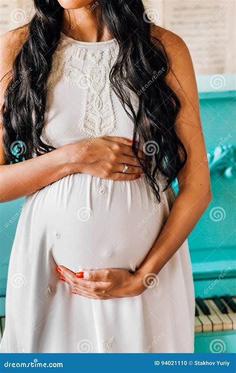 Beautiful Pregnant Woman Dressed In White Dress Touches Her Belly Stock