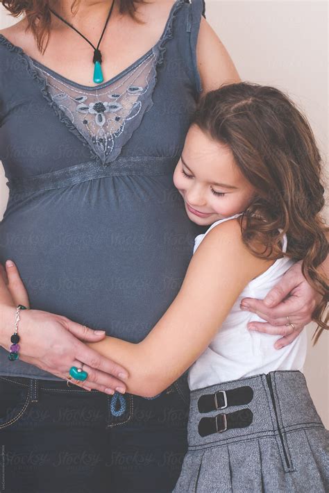 girl hugging her pregnant mother s bump by stocksy contributor lea