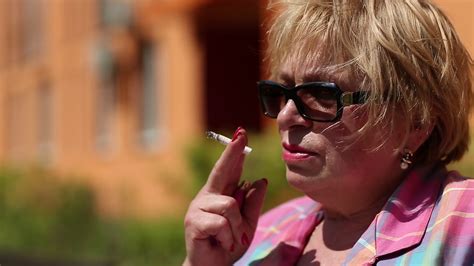 Senior Woman Sits On The Bench And Smokes A Cigarette Blonde Woman