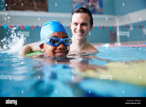 male swimming coach giving boy holding float    lesson  pool stock photo alamy