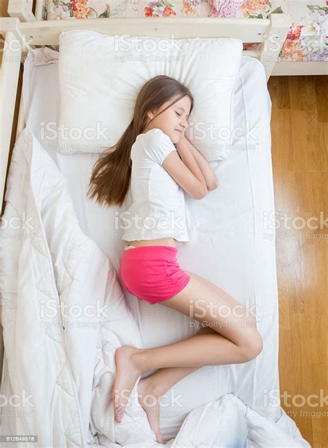 brunette teenage girls in pink pajamas sleeping on bed