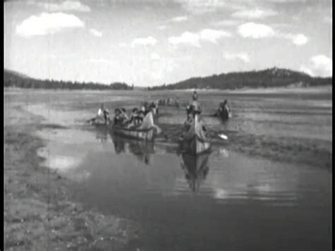 native americans paddling down river on canoe stock
