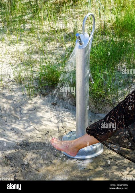 woman removing sand   legs  beach shower  sandy dune