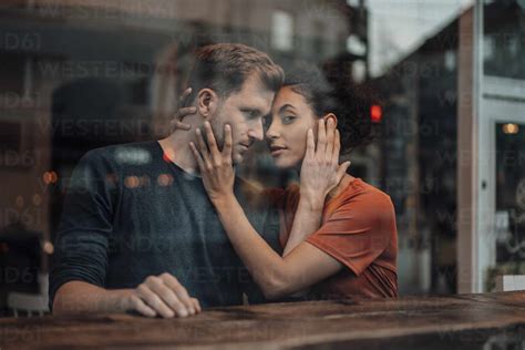 Romantic Couple Touching Each Others Faces At Cafe Seen Through Window