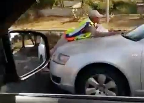 watch traffic cop hangs on to car as driver speeds off