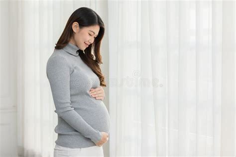 Happy Pregnant Woman Turtleneck Sweatshirt Standing In Front Of Windows