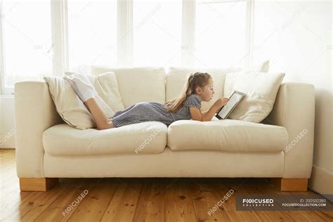 Young Girl Lying On Sofa With Digital Tablet — Connections Lying On