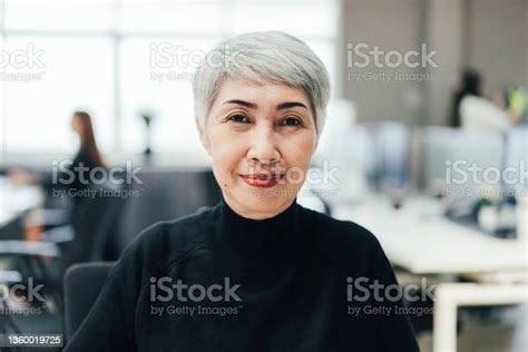 Portrait Of Asian Senior Female Manager At Desk In The Office Looking